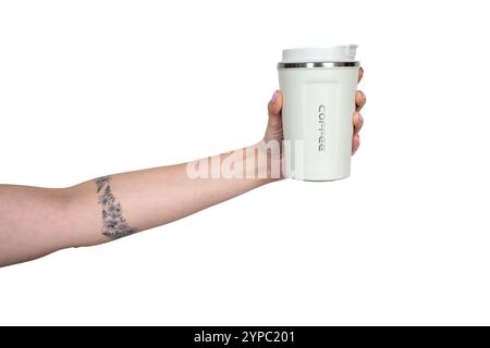 Main avec tatouage floral tenant une tasse de café réutilisable, favorisant la durabilité et des choix éco-responsables Banque D'Images