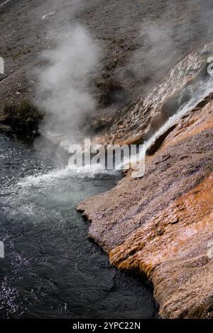 Une source de geyser active avec une décharge intermittente d'eau éjectée turbulemment et accompagnée de vapeur, parc national de Yellowstone, États-Unis Banque D'Images