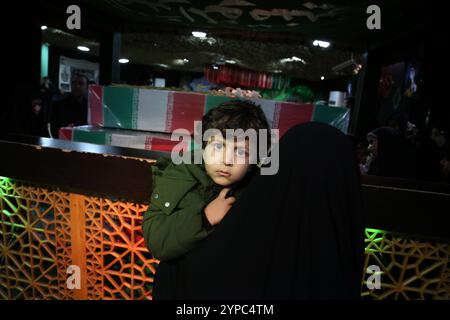 Téhéran, Iran. 29 novembre 2024. Une iranienne voilée tenant son enfant assiste aux funérailles du général de brigade Kiyomarth Porhashmi, un officier supérieur de la Force Qods du corps des gardiens de la révolution islamique (IRGC), tué à Alep, en Syrie. La Force Qods du CGRI est une unité de la Garde révolutionnaire iranienne qui mène des opérations militaires, de renseignement et de soutien à l'étranger pour faire progresser l'influence régionale de l'Iran. (Crédit image : © Rouzbeh Fouladi/ZUMA Press Wire) USAGE ÉDITORIAL SEULEMENT! Non destiné à UN USAGE commercial ! Banque D'Images