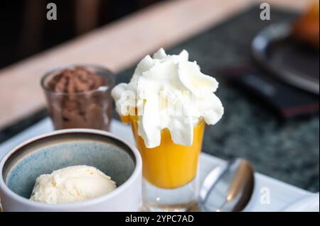 Café servi avec des desserts sucrés comme un gâteau, une cuillère à glace à la vanille et une crème anglaise à Louvain, en Belgique Banque D'Images