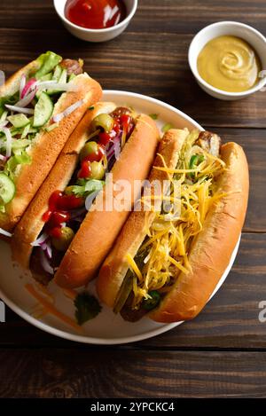 Hot-dogs chargés de garnitures assorties sur une table en bois. Vue rapprochée Banque D'Images