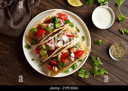 Tacos avec des légumes et de la viande sur plaque blanche sur fond en bois. Vue de dessus, pose à plat Banque D'Images