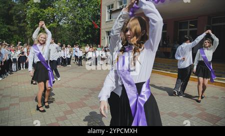 Berezovka, Biélorussie - 31 mai 2024 : des étudiants adolescents portant des écharpes dansent la valse lors de leur cérémonie de remise des diplômes dans la cour d'école, célébrant le Banque D'Images