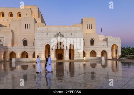 Les hommes locaux traversent la place principale en face de l'Opéra Royal à l'heure bleue, Mascate, péninsule arabique, Sultanat d'Oman Banque D'Images