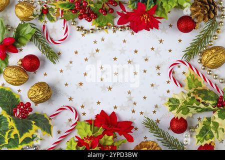 Cadre fait de décorations de Noël, telles que des branches de sapin, des boules, des noix, des cannes de bonbons sur un fond blanc avec des étoiles dorées, salle de copie Banque D'Images