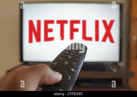 20 avril 2024, Brésil. Dans cette illustration photo, une main tenant une télécommande de téléviseur devant le logo Netflix sur un écran de télévision Banque D'Images