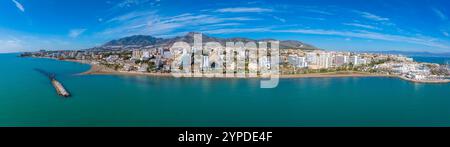 Vue aérienne de Benalmadena, en Espagne, avec un port de plaisance avec des bateaux amarrés, une architecture moderne et traditionnelle, et une toile de fond de montagnes escarpées. Banque D'Images