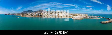 Vue aérienne de Benalmadena, Espagne, avec une marina avec des bateaux, des gratte-ciel et les montagnes de la Sierra de Mijas sous un ciel bleu clair. Banque D'Images