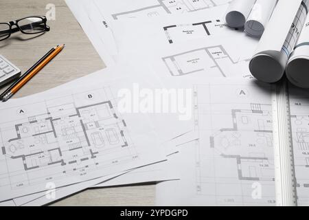 Différents dessins architecturaux, verres, règle et crayons sur table en bois, gros plan Banque D'Images