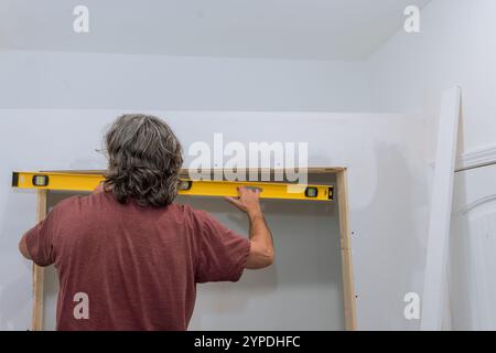 Travailleur avec cadre en bois de niveau qu'il construit la rénovation de la maison a lieu à l'intérieur sur des travaux de précision. Banque D'Images