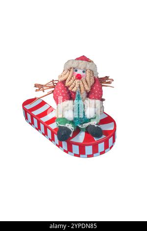 Rag poupée Père Noël tient un arbre de Noël et se trouve sur une canne de bonbons géante rayée blanche rouge surdimensionnée qui ressemble à un bateau ou un toboggan ou un coussin. Banque D'Images