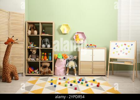 Cubes colorés sur tapis et jouets différents dans la chambre de l'enfant Banque D'Images