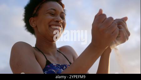 Vue en bas angle de femme afro-américaine jouant avec du sable sur la plage Banque D'Images