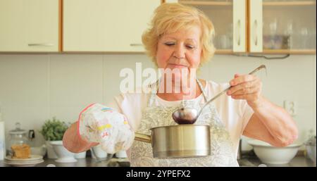 Femme senior préparant la confiture dans la cuisine Banque D'Images