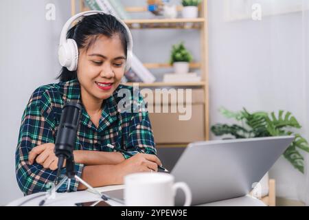 Femme portant des écouteurs assis à un bureau parlant dans le microphone et l'enregistrement d'un podcast, streaming en ligne à la maison, enregistrer podcast interview f Banque D'Images