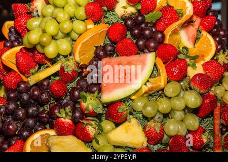 Fond de fruits coloré avec fraises, raisins, ananas, oranges et melon - mélange frais et juteux Banque D'Images