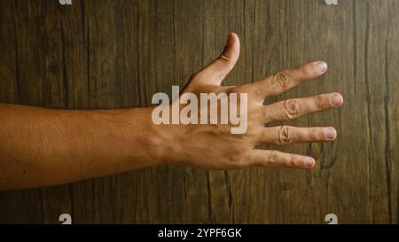 La main de l'homme s'est étirée sur un fond en bois montrant les doigts et la texture de la peau de façon éclatante Banque D'Images