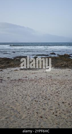 La plage de Lanzarote en journée avec un ciel nuageux et des rivages rocheux, représentant une scène extérieure sereine sur la côte des îles canaries. Banque D'Images