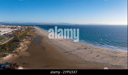 Le littoral de Tarifa présente des kite surfeurs et des cerfs-volants colorés. Les bâtiments blancs de la ville sont visibles, avec la côte africaine faiblement vue à travers la rue Banque D'Images