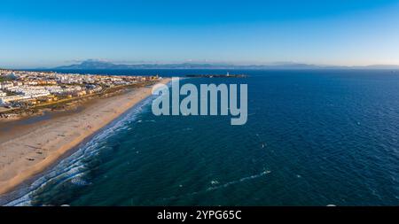 Tarifa, en Espagne, possède des plages de sable, des bâtiments blancs et des kite surfeurs. Un phare se dresse sur une péninsule, avec les montagnes du Rif visibles à travers la rue Banque D'Images