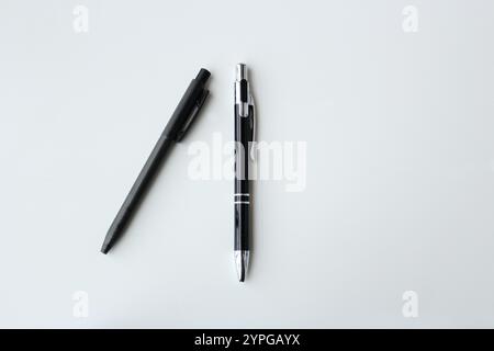 Deux stylos noirs isolés sur fond blanc avec espace pour la copie. Design de bannière minimaliste, simple et élégant. Fournitures de bureau, papeterie scolaire. Banque D'Images