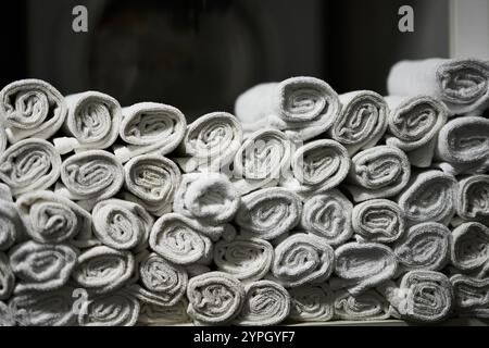 Serviettes blanches soigneusement enroulées empilées pour l'affichage dans un environnement de spa Banque D'Images