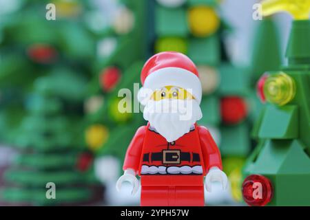 Tambov, Fédération de Russie - 30 novembre 2024 Une figurine Lego Santa Claus debout devant des arbres de Noël. Gros plan. Banque D'Images