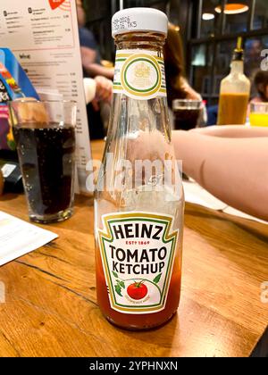 Une bouteille de ketchup Heinz Tomato sur une table dans un restaurant est presque vide. Banque D'Images