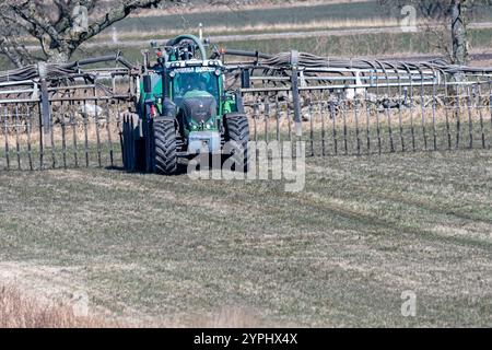 Un tracteur équipé de la technologie moderne tend au champ, préparant le sol pour la plantation de cultures sous ciel dégagé dans une zone rurale Banque D'Images