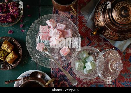 Plat coucher/vue de dessus de Rose et Pistachio Turkish Delight (Lokkum) sur un tapis turc, servi avec du thé turc. Antalya, Türkiye. Banque D'Images