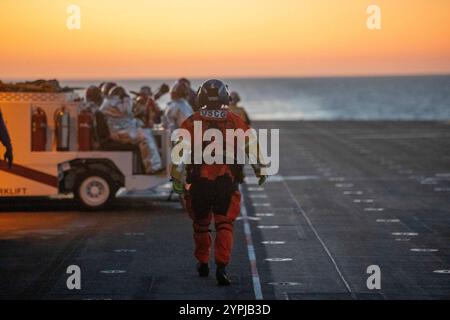 241120-N-IL330-1399 Un membre de l'équipage d'un hélicoptère MH-60 Jayhawk de la Garde côtière se prépare à évacuer médicalement un marin du pont d'envol à bord du porte-avions amphibie USS Tripoli (LHA 7) pendant les opérations de vol, le 20 novembre 2024. Le Tripoli est un navire d'assaut amphibie de classe américaine, domicilié à San Diego. Tripoli est en cours dans la zone d'opérations de la 3e flotte des États-Unis menant une formation tactique avancée qui améliore la capacité de combat et la compétence tactique. (Photo de l'US Navy par Austyn Riley, spécialiste des communications de masse, 2e classe) Banque D'Images