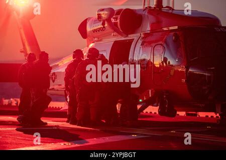 241120-N-IL330-1558 des marins et un membre de l'équipage d'un hélicoptère MH-60 Jayhawk de la Garde côtière évacuent médicalement un marin du pont d'envol à bord du porte-avions d'assaut amphibie USS Tripoli (LHA 7) pendant les opérations de vol, le 20 novembre 2024. Le Tripoli est un navire d'assaut amphibie de classe américaine, domicilié à San Diego. Tripoli est en cours dans la zone d'opérations de la 3e flotte des États-Unis menant une formation tactique avancée qui améliore la capacité de combat et la compétence tactique. (Photo de l'US Navy par Austyn Riley, spécialiste des communications de masse, 2e classe) Banque D'Images