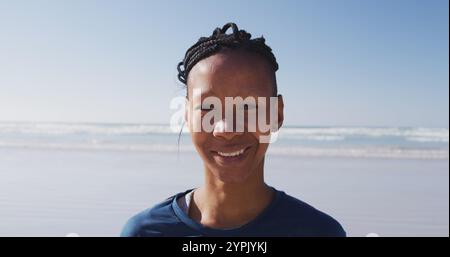 Portrait d'une femme afro-américaine attirante jouissant de l'exercice sur une plage par une journée ensoleillée, pract Banque D'Images