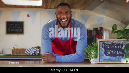 Portrait d'homme afro-américain portant un tablier souriant tout en se tenant dans le camion de nourriture. food truck et concept de nourriture de rue Banque D'Images