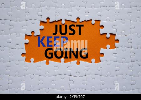 Symbole « continuez à aller ». Puzzle blanc avec des mots juste continuer. Beau fond orange. Business and Just Keep Go concept. Copier l'espace. Banque D'Images