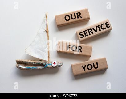 Notre service pour vous symbole. Blocs en bois avec des mots notre service pour vous. Beau fond blanc avec bateau. Affaires et notre service pour vous conce Banque D'Images