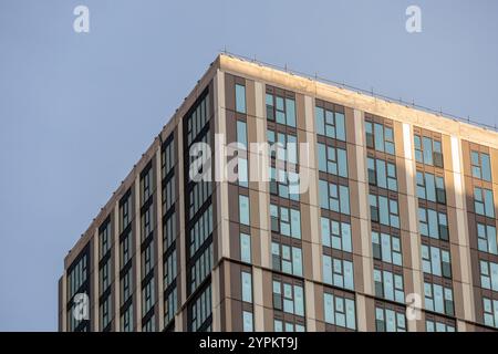 Façade moderne d'immeuble d'appartements à Canary Wharf avec motifs géométriques de fenêtres en verre et revêtement beige sur ciel dégagé Banque D'Images