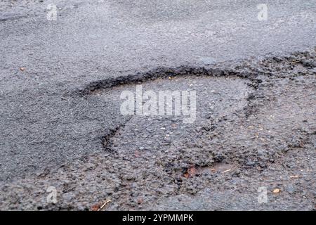 Taplow, Royaume-Uni. 30 novembre 2024. Les nids de poule sont réapparus à Marsh Lane, Taplow, Buckinghamshire. Certains automobilistes font un virage pour les éviter. Les réparations des nids-de-poule précédents sur ce tronçon de route ont été effectuées en mai 2023 par des entrepreneurs du conseil municipal du Buckinghamshire qui ont utilisé un nouveau système Velocity Patching pour remplir les milliers de nids-de-poule à travers Bucks. Le patcher Velocity force l'air à grande vitesse dans les nids de poule pour les éliminer, puis la zone est enduite de bitume froid pour créer un joint, avant que l'agrégat ne soit enduit de bitume et appliqué, à nouveau à grande vitesse. Les réparations n'ont cependant pas été effectuées Banque D'Images