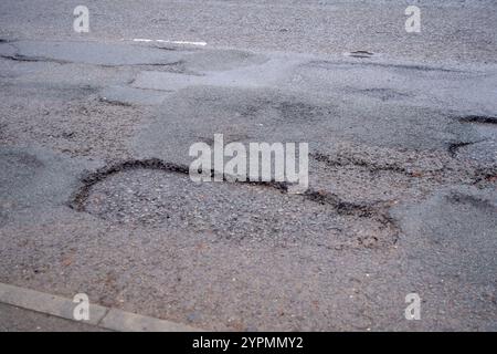 Taplow, Royaume-Uni. 30 novembre 2024. Les nids de poule sont réapparus à Marsh Lane, Taplow, Buckinghamshire. Certains automobilistes font un virage pour les éviter. Les réparations des nids-de-poule précédents sur ce tronçon de route ont été effectuées en mai 2023 par des entrepreneurs du conseil municipal du Buckinghamshire qui ont utilisé un nouveau système Velocity Patching pour remplir les milliers de nids-de-poule à travers Bucks. Le patcher Velocity force l'air à grande vitesse dans les nids de poule pour les éliminer, puis la zone est enduite de bitume froid pour créer un joint, avant que l'agrégat ne soit enduit de bitume et appliqué, à nouveau à grande vitesse. Les réparations n'ont cependant pas été effectuées Banque D'Images