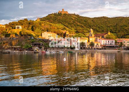 Hôtels, bars et restaurants sur la promenade de la plage de Collioure en contrebas du Fort Saint-Elme illuminé par le coucher du soleil, Languedoc-Roussillion, France Banque D'Images