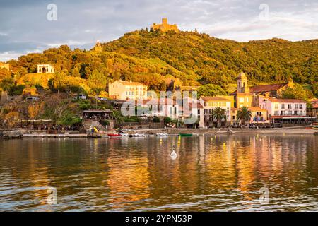 Hôtels, bars et restaurants sur la promenade de la plage de Collioure en contrebas du Fort Saint-Elme illuminé par le coucher du soleil, Languedoc-Roussillion, France Banque D'Images