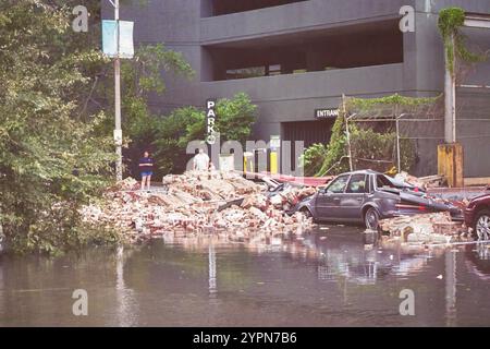 Nouvelle-Orléans, LOUISIANE, États-Unis - 29 août 2005 : une voiture brisée par des briques d'un mur effondré après le passage de l'ouragan Katrina plusieurs heures auparavant. Cela s'est produit à un pâté de maisons du Superdome au centre-ville. La photo a été prise avec un appareil photo 35 mm le matin après le passage de l'ouragan. La rue n'avait pas encore été complètement inondée par les digues brisées, mais elle le serait plusieurs heures plus tard. Banque D'Images