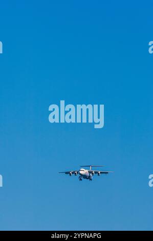 Un avion descend gracieusement à travers un ciel bleu vif par temps clair. L'avion est positionné pour atterrir dans une atmosphère sereine, showcasi Banque D'Images