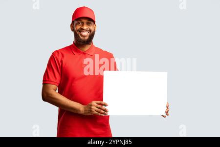 Un homme de livraison africain montrant une affiche blanche vide, un fond jaune, une maquette Banque D'Images