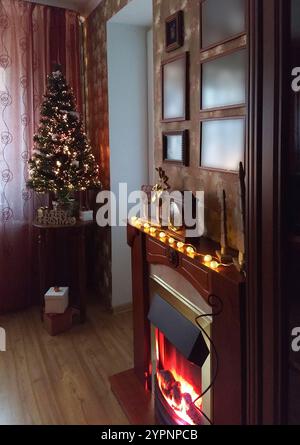 Salle de séjour festive agrémentée d'un sapin de Noël décoré, d'une cheminée et d'un éclairage chaleureux Banque D'Images