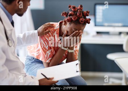 Vue latérale de la femme afro-américaine choquée pleurant lors de la consultation en clinique avec le médecin réconfortant patient, espace de copie Banque D'Images