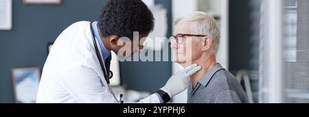 Image recadrée d'un médecin afro-américain portant des gants palpant soigneusement le cou d'un patient senior pendant l'examen en clinique, espace de copie Banque D'Images