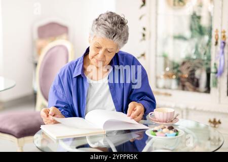 Femme senior profitant d'un après-midi tranquille lecture dans un café confortable Banque D'Images