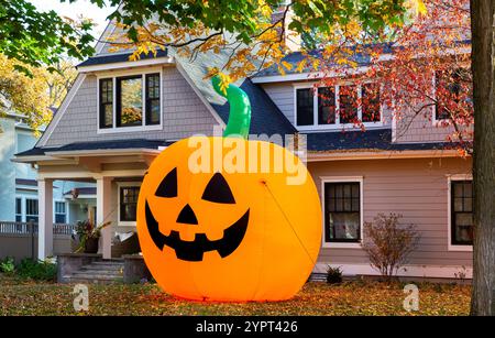 Une énorme décoration de citrouille gonflable orange vif Jack-o’-Lantern pour Halloween dans la cour avant d'une maison, Minneapolis, Minnesota. Banque D'Images