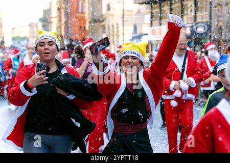 Les coureurs célèbrent pendant le Liverpool Santa Dash. Les participants ont enfilé des costumes rouges (et bleus) du Père Noël le long d'un parcours de 5 km autour du centre-ville de Liverpool pour soutenir le Claire House Children's Hospice. 8 500 personnes ont participé à la 20e édition annuelle de Liverpool Santa Dash. Banque D'Images